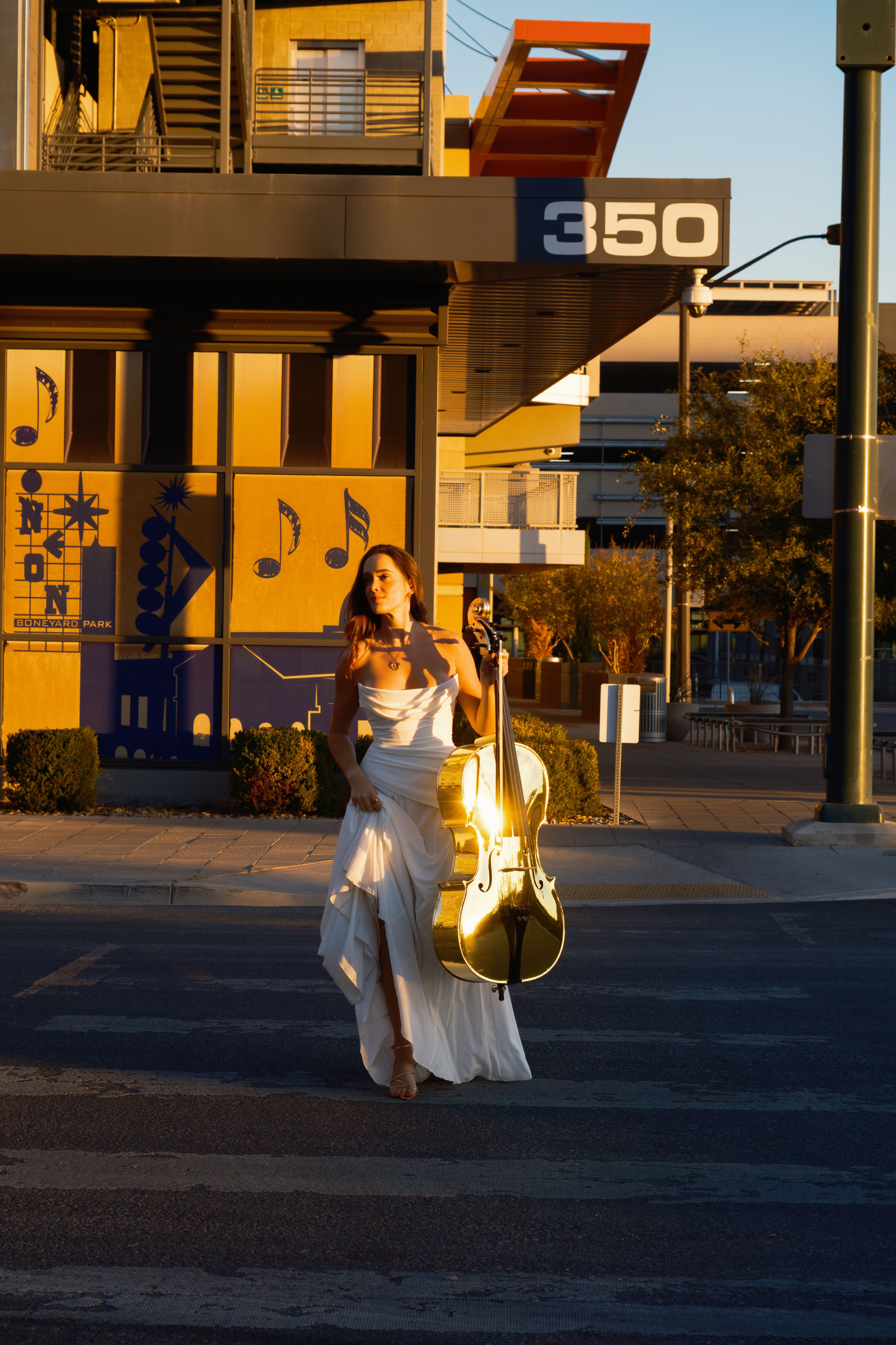Golden Cello Girl walking across the street with golden cello at dusk