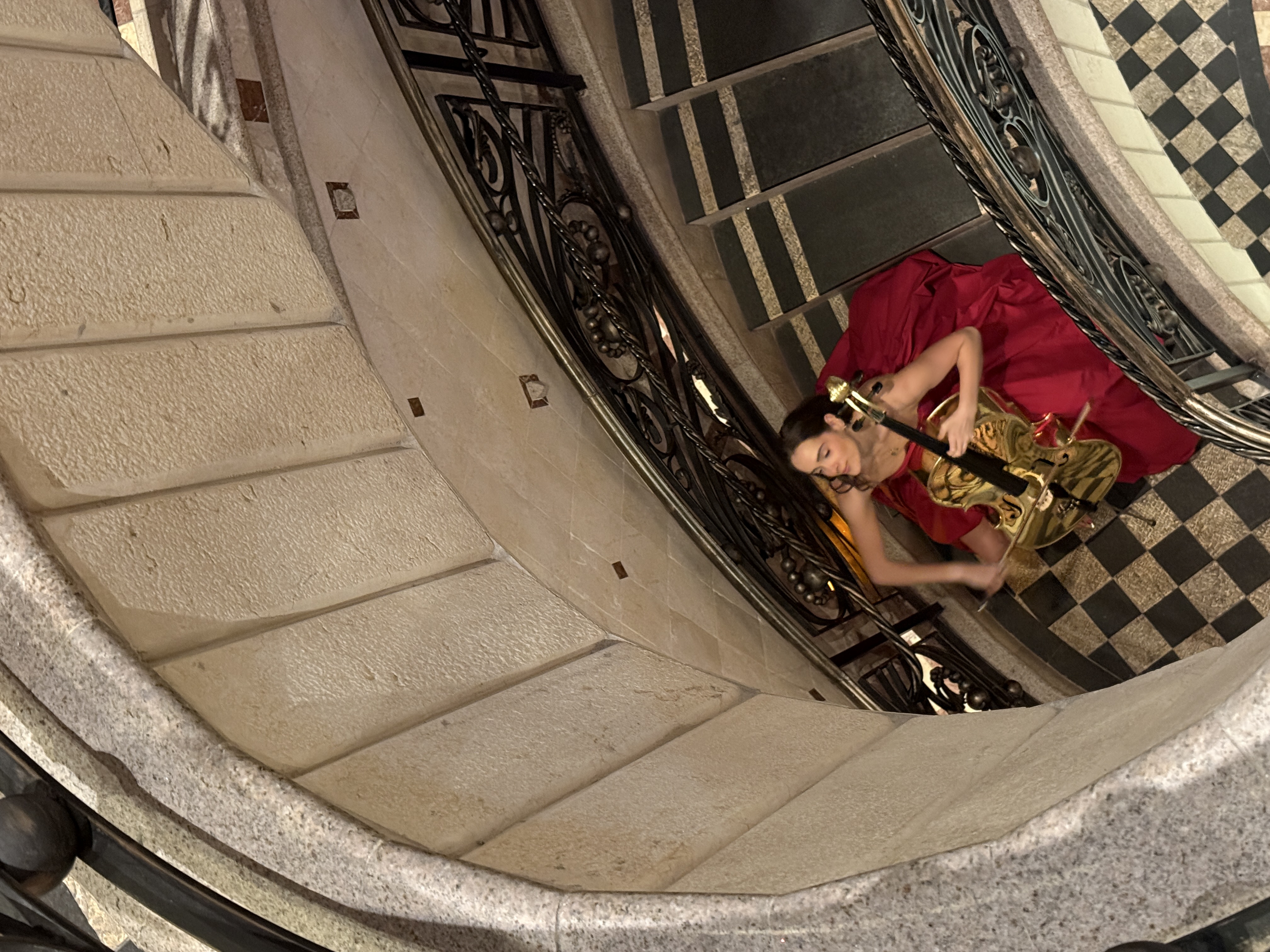 Elegant spiral staircase performance in flowing red gown